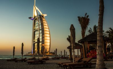 Burj Al Arab hotel of Dubai and beach view with palm tree, deck and chairs